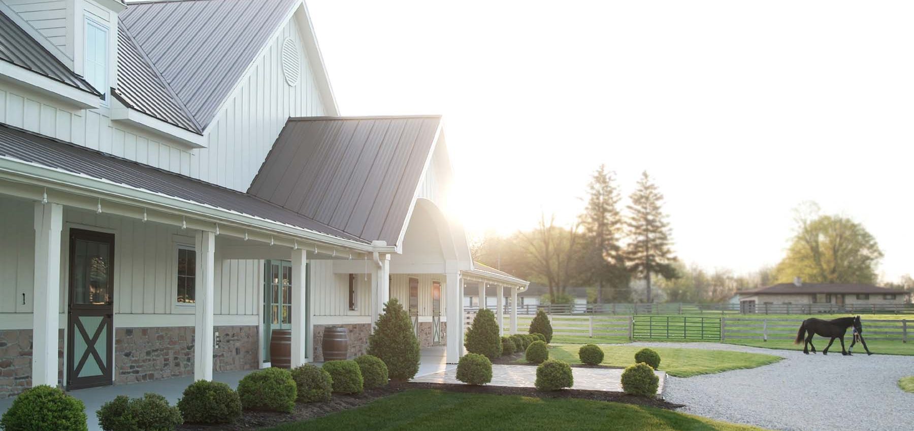 Cherith Brook Farm exterior of barn. Horse and trainer in the background