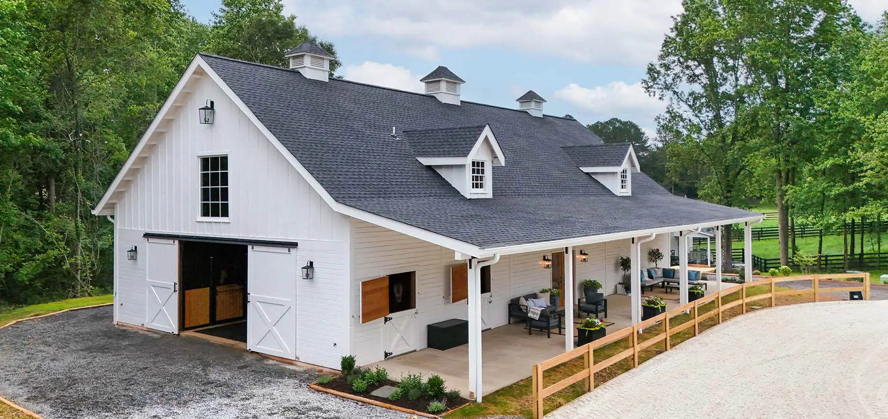Exterior side view of private barn end doors and riding arena