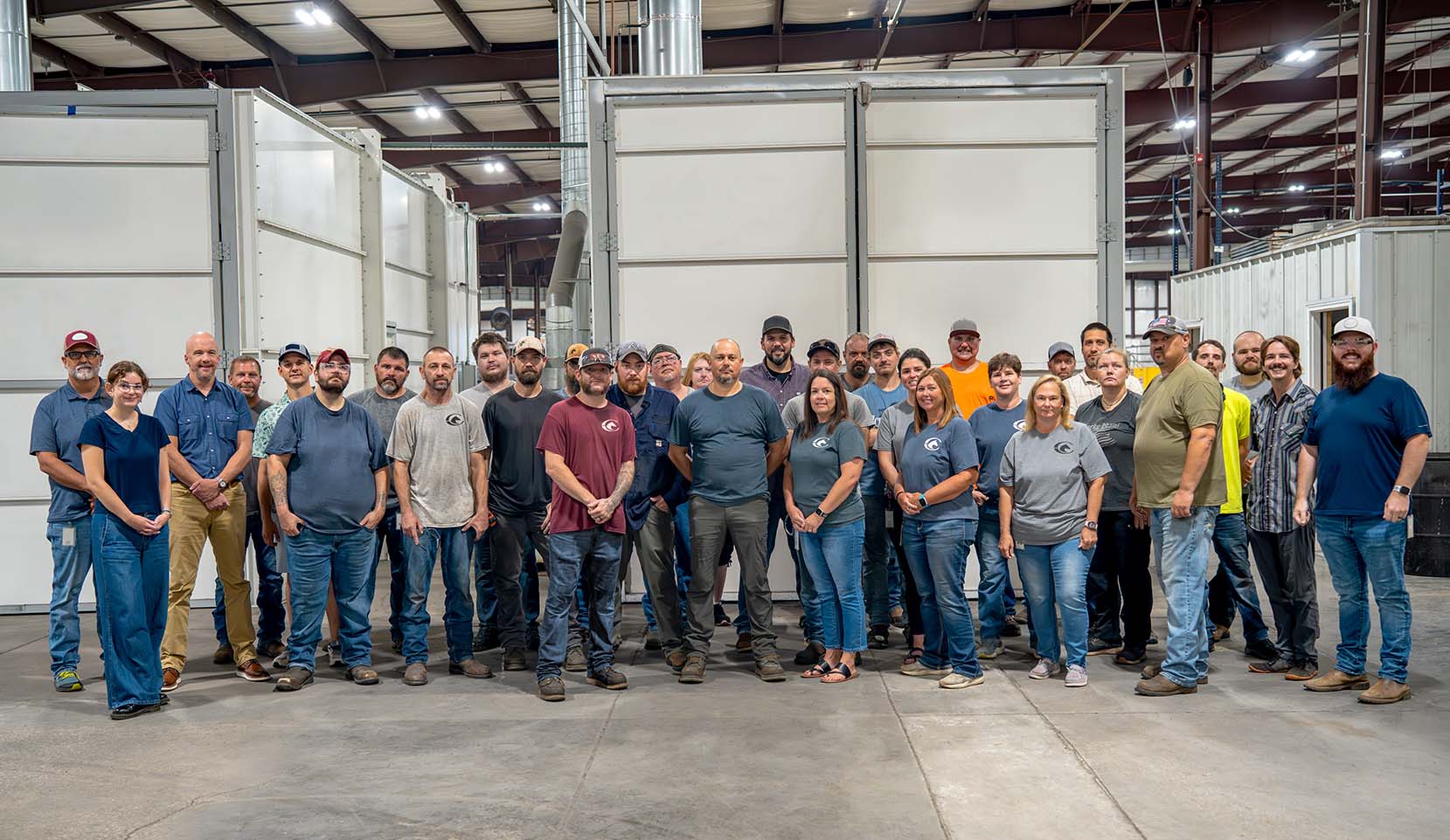 Classic Equine Equipment team on the shop floor with powder-coat machines in the background.