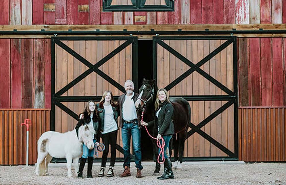 Michell Payne, family and horses in front of barn.
